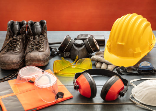 Safety gear on a table: boots, goggles, hardhat, masks, and headphones