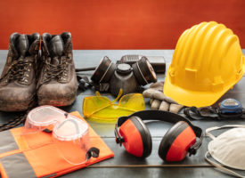Safety gear on a table: boots, goggles, hardhat, masks, and headphones